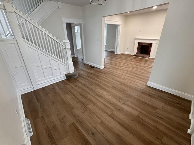 unfurnished living room with dark hardwood / wood-style floors and a brick fireplace