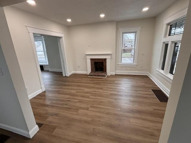 unfurnished living room with dark hardwood / wood-style floors and a brick fireplace