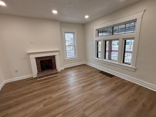 unfurnished living room featuring a wealth of natural light, a fireplace, and dark hardwood / wood-style floors