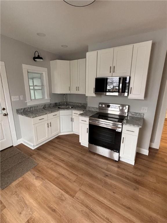 kitchen with white cabinets, hardwood / wood-style floors, stainless steel appliances, and sink