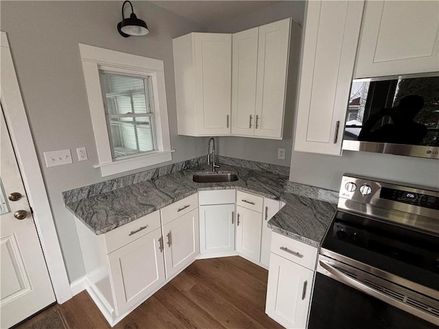 kitchen featuring sink, stainless steel appliances, dark hardwood / wood-style flooring, dark stone counters, and white cabinets