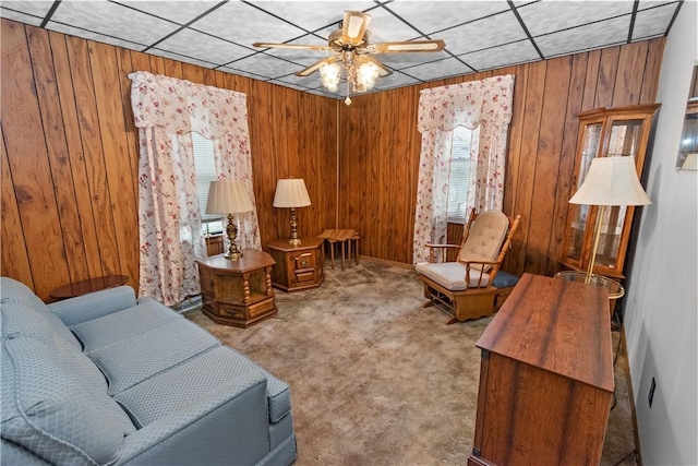 sitting room featuring carpet, ceiling fan, and wood walls