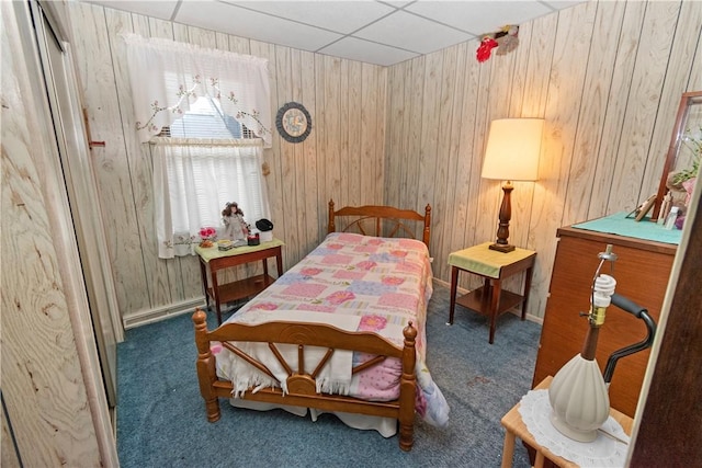 bedroom with a paneled ceiling, wooden walls, and dark colored carpet