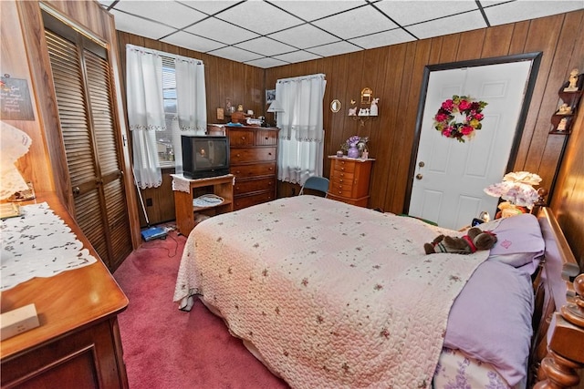 carpeted bedroom featuring wooden walls and a closet