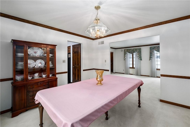 dining space with a notable chandelier, light colored carpet, and crown molding