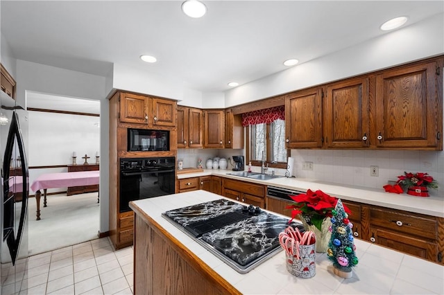 kitchen with black appliances, tasteful backsplash, sink, and tile countertops