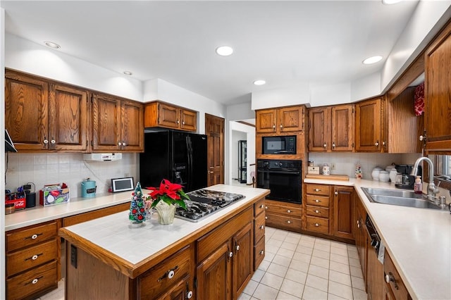 kitchen with black appliances, decorative backsplash, a kitchen island, and sink