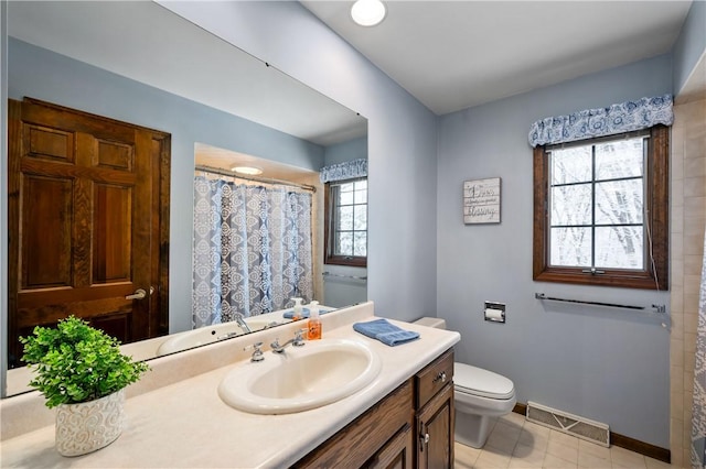 bathroom featuring tile patterned flooring, plenty of natural light, toilet, and vanity