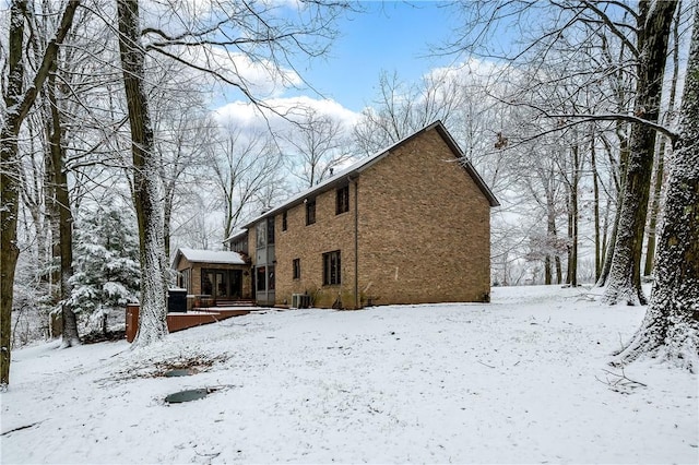 snow covered property featuring central AC unit and a deck