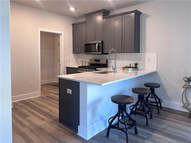 kitchen featuring sink, stainless steel appliances, a kitchen breakfast bar, dark hardwood / wood-style floors, and backsplash