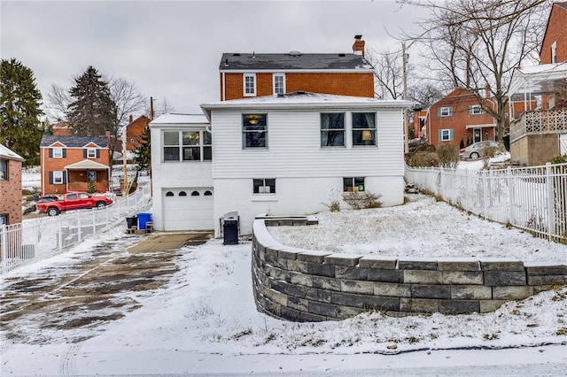 snow covered rear of property with a garage