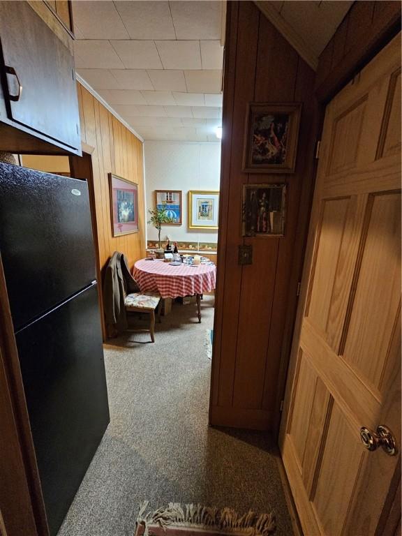 hall featuring carpet, ornamental molding, and wood walls