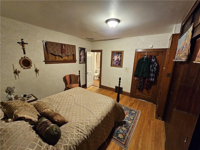 bedroom featuring connected bathroom and light hardwood / wood-style floors