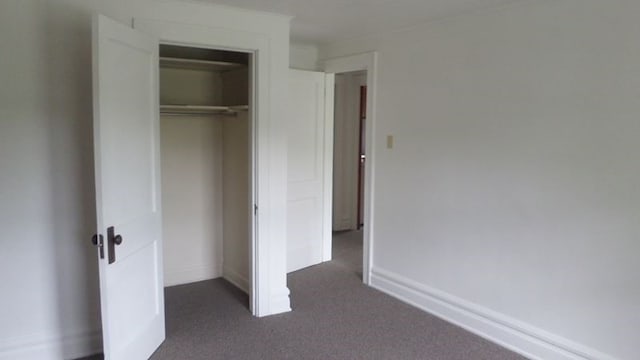 unfurnished bedroom with dark carpet and a closet