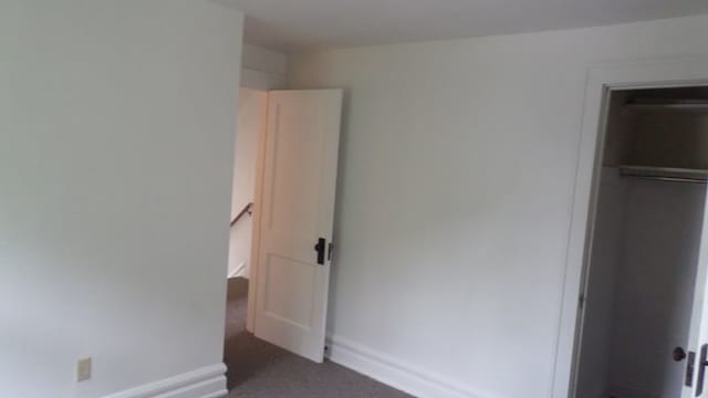 unfurnished bedroom featuring dark colored carpet and a closet