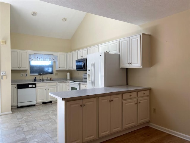 kitchen featuring white cabinetry, sink, kitchen peninsula, vaulted ceiling, and white appliances