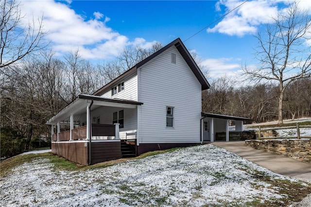 snow covered property with covered porch and a carport