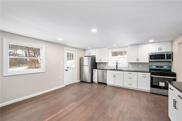 kitchen featuring white cabinetry, sink, stainless steel appliances, dark hardwood / wood-style flooring, and decorative backsplash