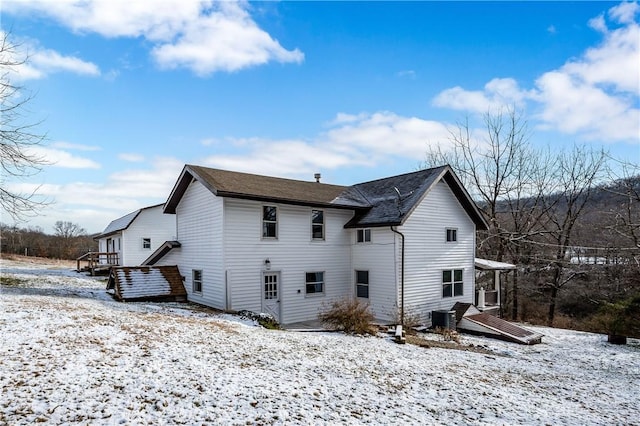 snow covered rear of property featuring central AC unit