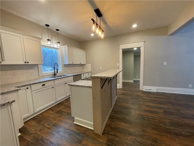 kitchen featuring light stone counters, sink, a center island, and hanging light fixtures