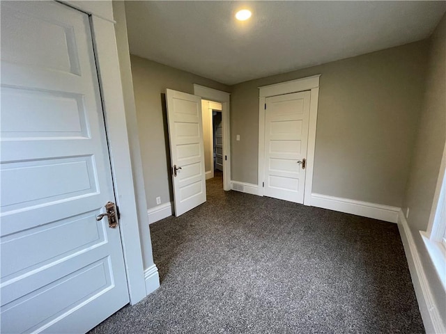 unfurnished bedroom with dark carpet and a closet