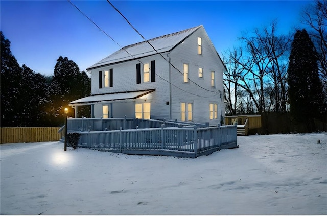 snow covered house with a wooden deck