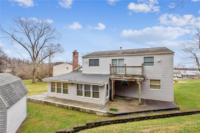 rear view of property featuring a storage unit, a lawn, and a wooden deck