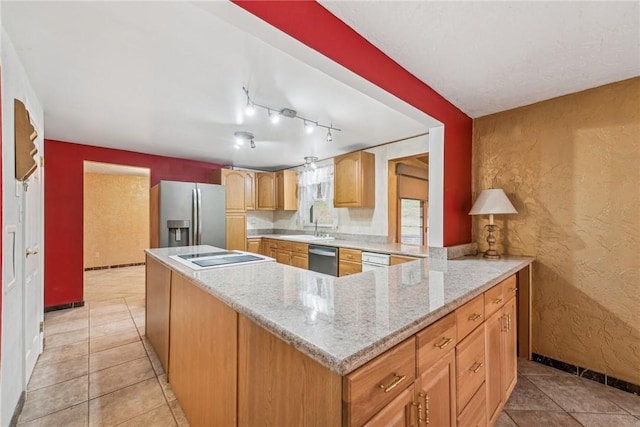 kitchen with light stone countertops, kitchen peninsula, sink, and appliances with stainless steel finishes