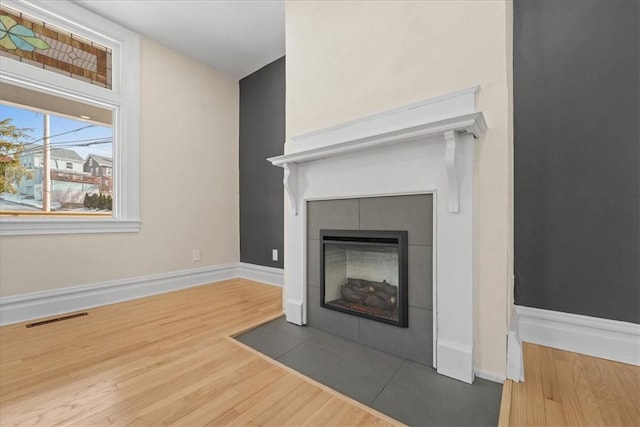 interior details featuring hardwood / wood-style flooring and a tiled fireplace