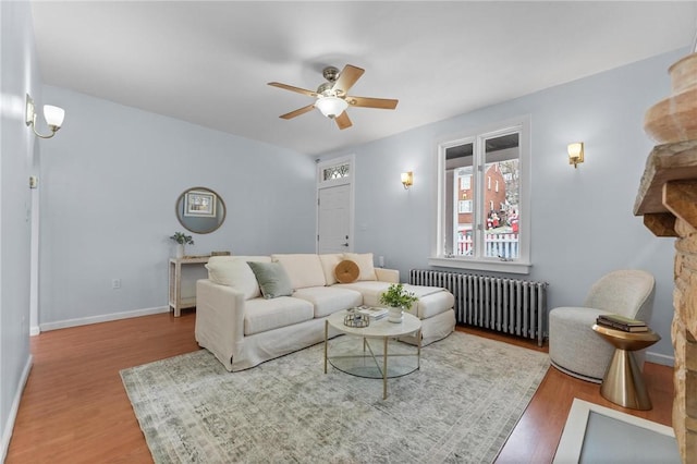 living room featuring wood-type flooring, radiator, and ceiling fan