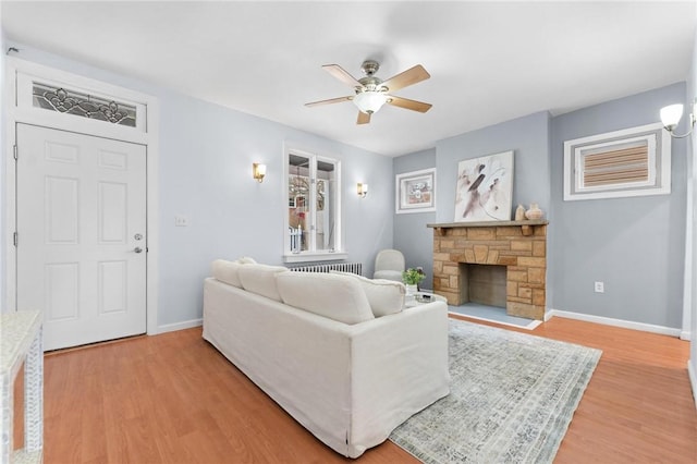 living room with ceiling fan, wood-type flooring, and a fireplace