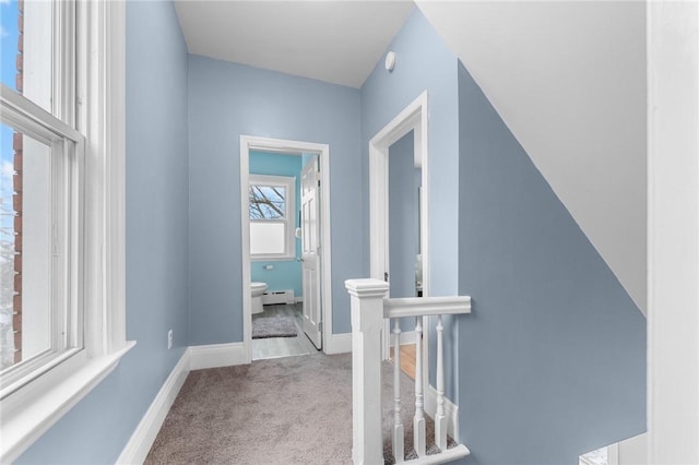 hall featuring light colored carpet and baseboard heating