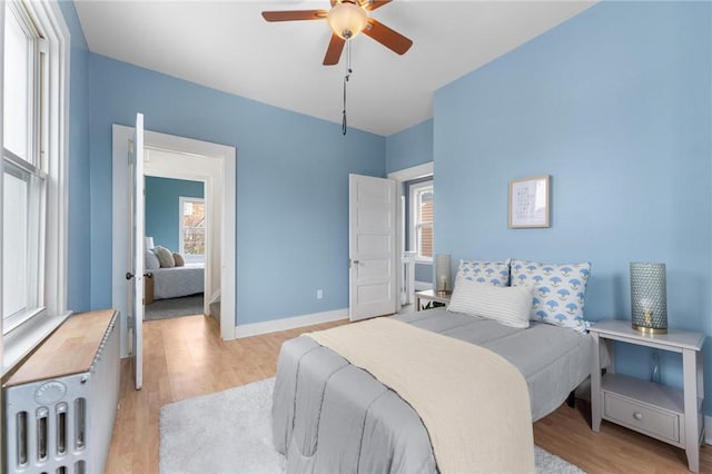 bedroom with multiple windows, light hardwood / wood-style floors, and ceiling fan