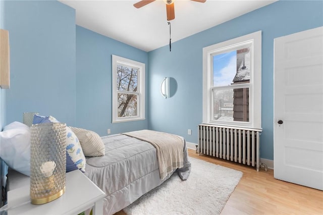 bedroom featuring ceiling fan, radiator heating unit, and light wood-type flooring