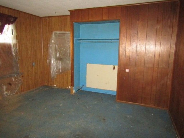 unfurnished bedroom with a closet and wooden walls