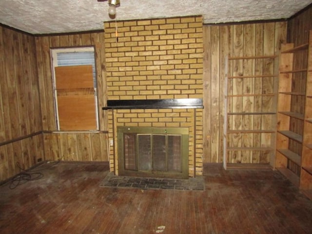 unfurnished living room featuring wooden walls, a fireplace, a textured ceiling, and hardwood / wood-style flooring