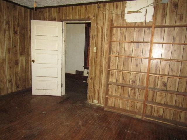 empty room featuring dark wood-type flooring and wooden walls