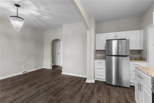 kitchen with white cabinets, stainless steel fridge, light stone counters, and hanging light fixtures