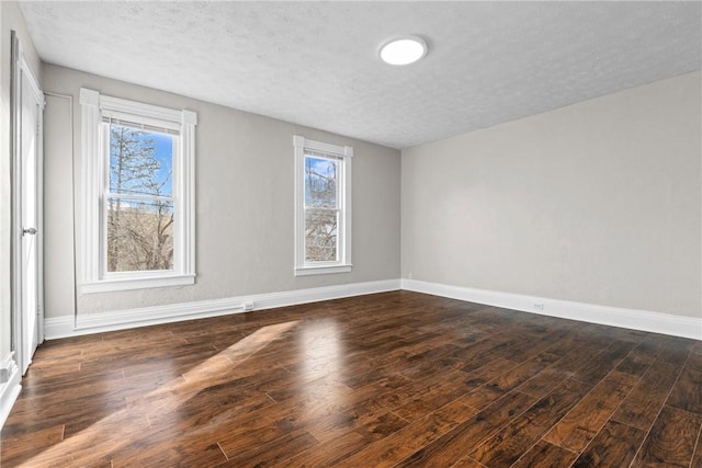 unfurnished room featuring a wealth of natural light, dark wood-type flooring, and a textured ceiling