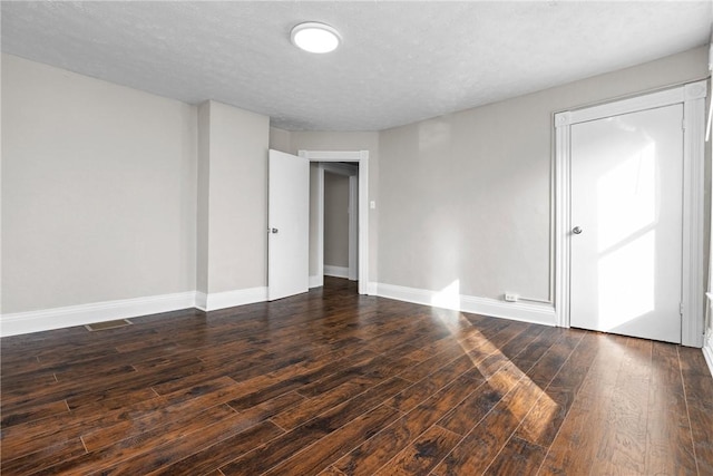 unfurnished room with a textured ceiling and dark hardwood / wood-style floors