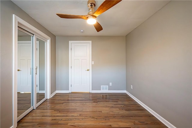 unfurnished bedroom featuring a closet, ceiling fan, and dark wood-type flooring