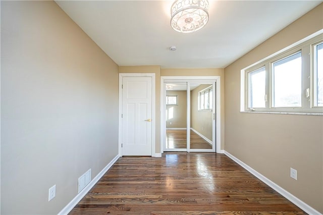 unfurnished bedroom featuring a closet and dark wood-type flooring