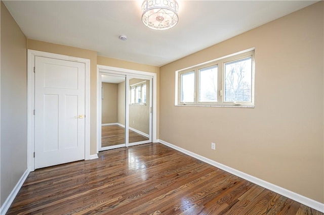 unfurnished bedroom with dark hardwood / wood-style flooring and a closet