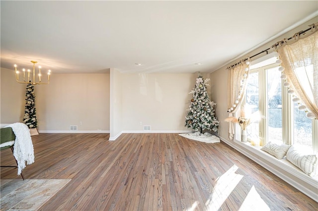 spare room with wood-type flooring and a notable chandelier