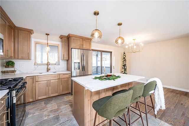 kitchen with pendant lighting, a breakfast bar, a center island, sink, and stainless steel appliances