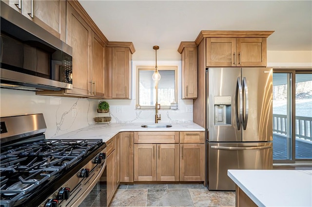 kitchen featuring decorative backsplash, appliances with stainless steel finishes, light stone counters, sink, and pendant lighting