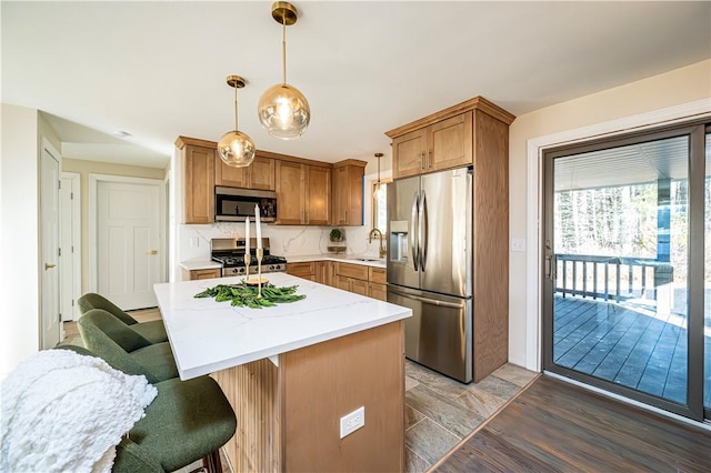 kitchen with dark hardwood / wood-style flooring, stainless steel appliances, sink, pendant lighting, and a center island