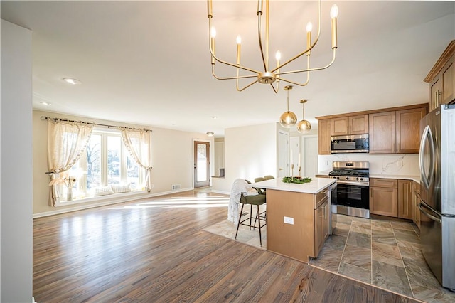 kitchen with a kitchen bar, appliances with stainless steel finishes, decorative light fixtures, a center island, and dark hardwood / wood-style floors