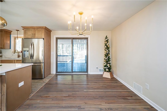 kitchen with sink, dark wood-type flooring, stainless steel fridge, a chandelier, and pendant lighting