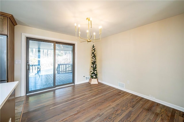 unfurnished dining area featuring dark wood-type flooring and a chandelier